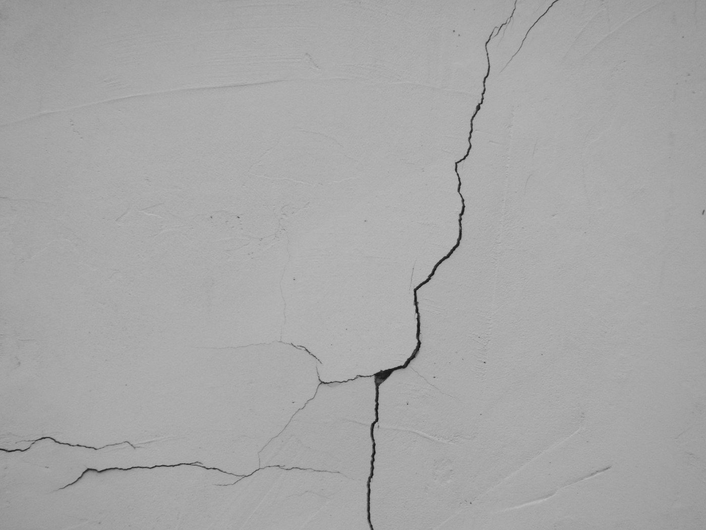 A stress crack meanders across pale stucco with hairline branches.