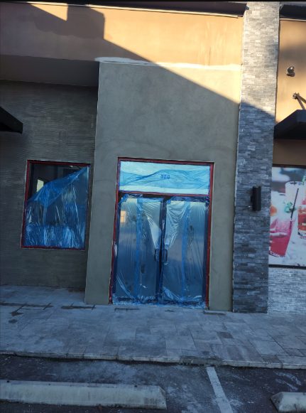 Completed storefront stucco and stone veneer on commercial building with masked windows